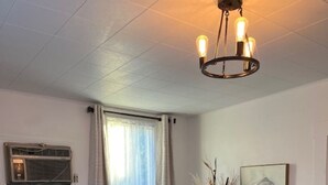 A dining area with a wooden table and chairs, a black cabinet, a painting, and an air conditioning unit on the wall. - Charming 2-bedroom home in Odessa (Odessa)