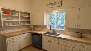 A kitchen with white cabinets, a dishwasher, a sink, and a window with a view of greenery. - Charming 2-bedroom home in Odessa (Odessa)