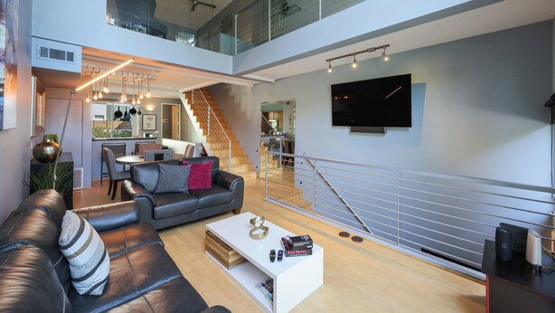 A modern living space with a staircase, a flat-screen TV, and a dining area.