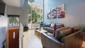 A modern living room with a large window, a sofa, a coffee table, and artwork on the wall.