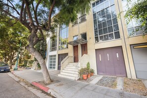 A two-story building with a staircase leading to the entrance, a car parked on the street, and potted plants on the sidewalk. - Luxury-award winning loft Townhouse, top location (San Diego)