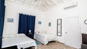 Een kamer met twee bedden, een plafondventilator, een airconditioning en een deur.