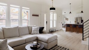 A modern living room with a sectional sofa, a coffee table, and a kitchen area with bar stools. - Updated & Spacious 5-bedroom house with Views of the Rock and Mountains  (Castle Rock)