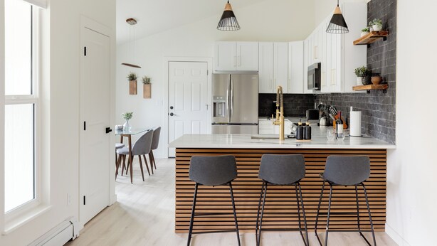 A modern kitchen with a central island, bar stools, pendant lighting, and built-in shelving. - Updated & Spacious 5-bedroom house with Views of the Rock and Mountains  (Castle Rock)