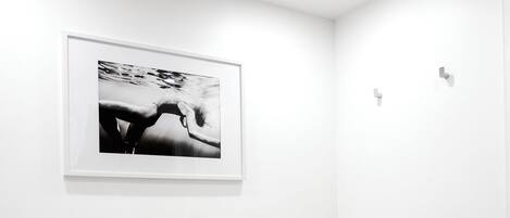 A modern bathroom with a freestanding bathtub, a framed photograph on the wall, and a small wooden stool.
