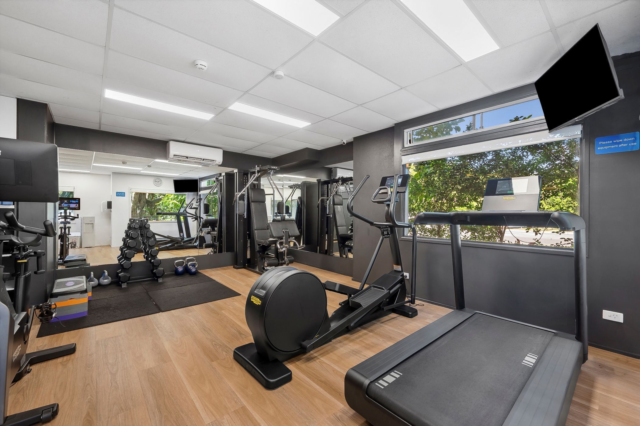 A gym with cardio machines, weightlifting equipment, and a treadmill.