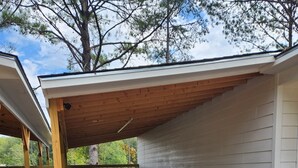 Ein überdachter Außenbereich mit Kiesboden, Holzbalken und einer weißen Wand.