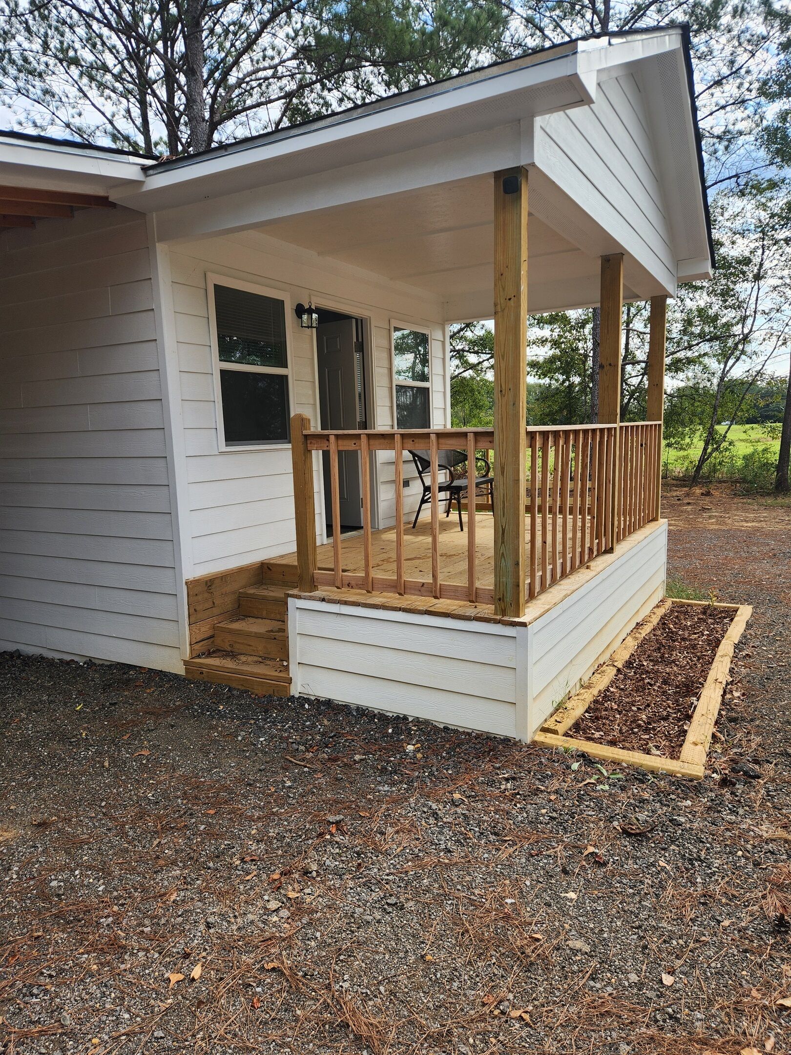 A small, single-story building with a covered porch and a wooden deck.