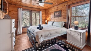 A wooden cabin bedroom with a bed, dresser, and a ceiling fan. - Relax to Creek Sounds • Hot Tub Cabin • Firepit BBQ (Cherry Log)