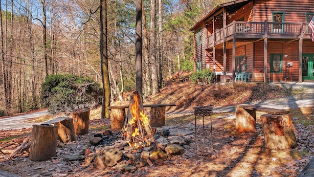 A rustic cabin with a fire pit surrounded by wooden benches and a porch. - Relax to Creek Sounds • Hot Tub Cabin • Firepit BBQ (Cherry Log)