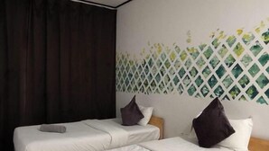 Habitación de hotel con dos camas, cada una con ropa de cama y almohadas blancas, y un panel decorativo en la pared.