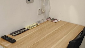 Una mesa de madera con un control remoto, un teléfono y una fila de cartas.