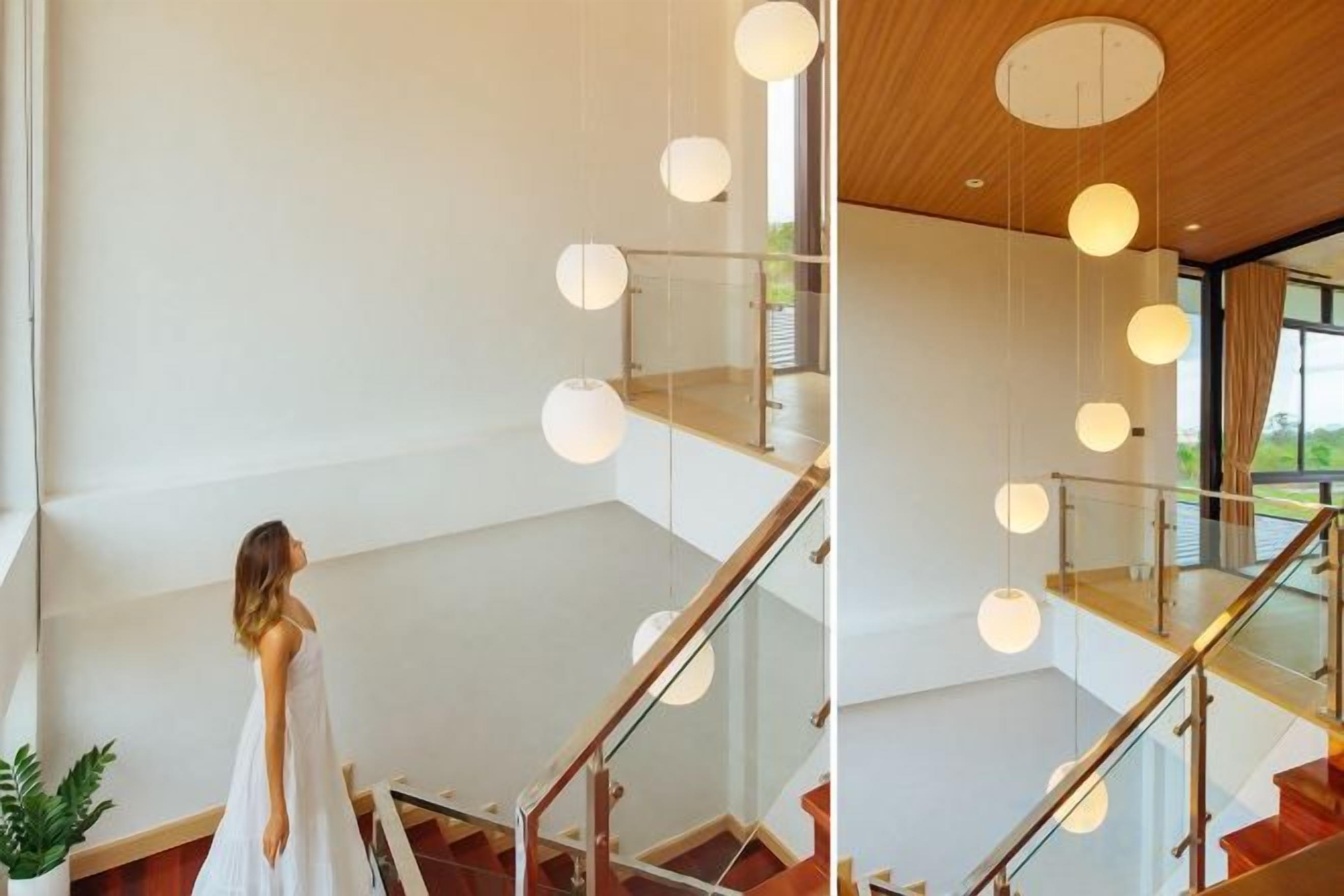 A staircase with glass railings and pendant lighting.