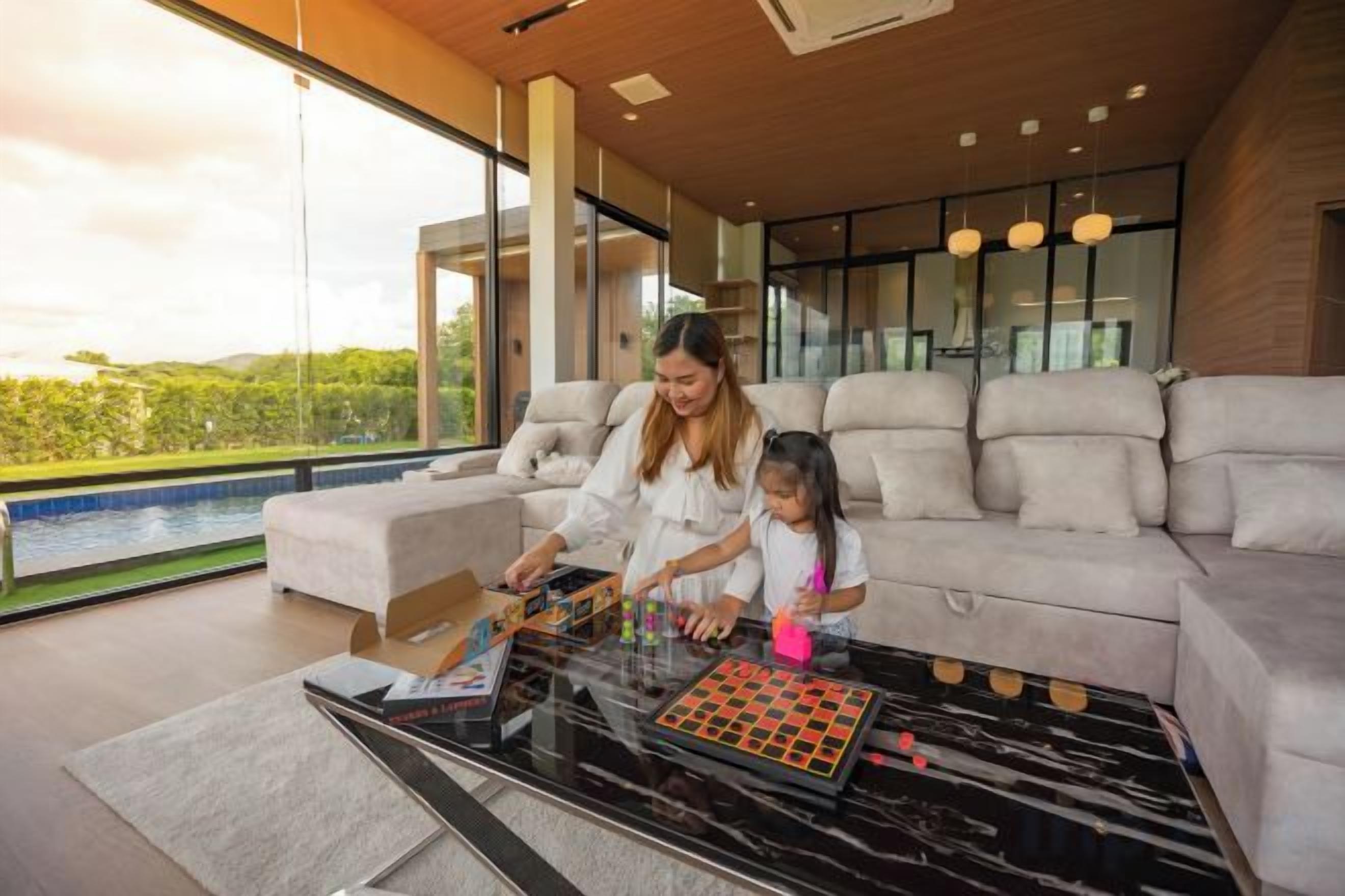 A modern living room with a glass coffee table, a sofa, and a view of a swimming pool.