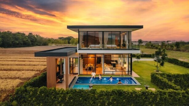 Une maison moderne à deux étages, dotée d’une piscine, de grandes baies vitrées et d’une pelouse bien entretenue.