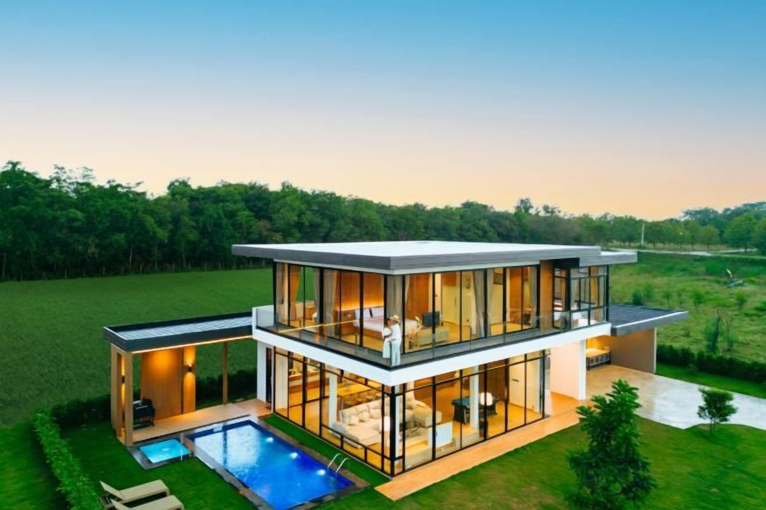 Een modern herenhuis met zwembad, grote glasramen en een verzorgd gazon.
