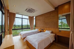 A hotel room with two beds, large windows, a wooden headboard, and a view of the outdoors. - Krajokkaew Mouthten Khao Yai (Pak Chong)