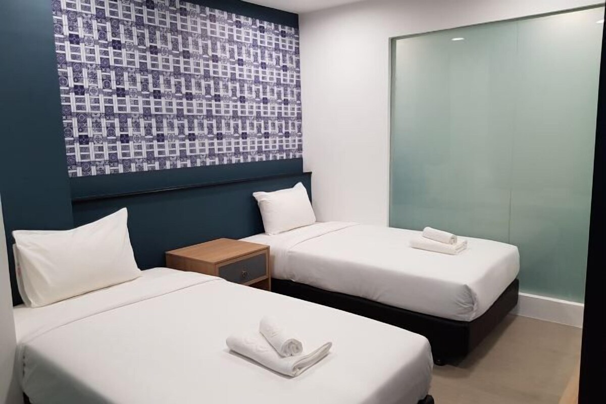 Ein Hotelzimmer mit zwei Betten, einer Wand mit Muster und einer Schiebetür.