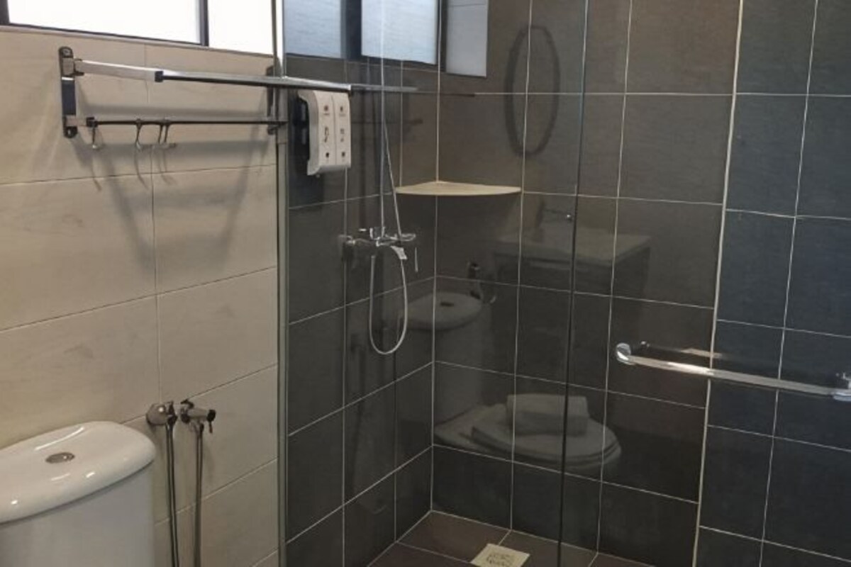 Een badkamer met een toilet, een douche en een handgreep.