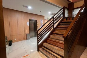 Un escalier en bois, doté d’une rampe, mène à un ascenseur.