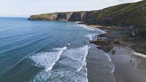 A coastal beach with rocky cliffs and a clear view of the ocean.