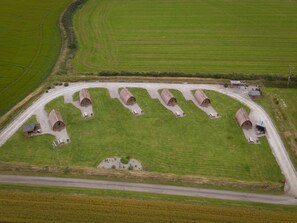 Vista aérea de una propiedad rural con seis estructuras cilíndricas, un camino de grava y campos verdes circundantes.