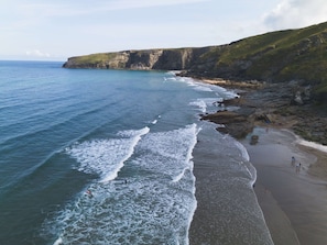 A coastal beach with rocky cliffs and a clear view of the ocean.