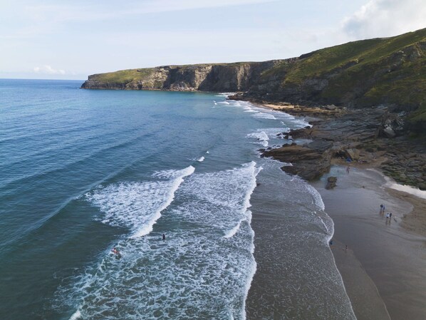 A coastal beach with rocky cliffs and a clear view of the ocean.