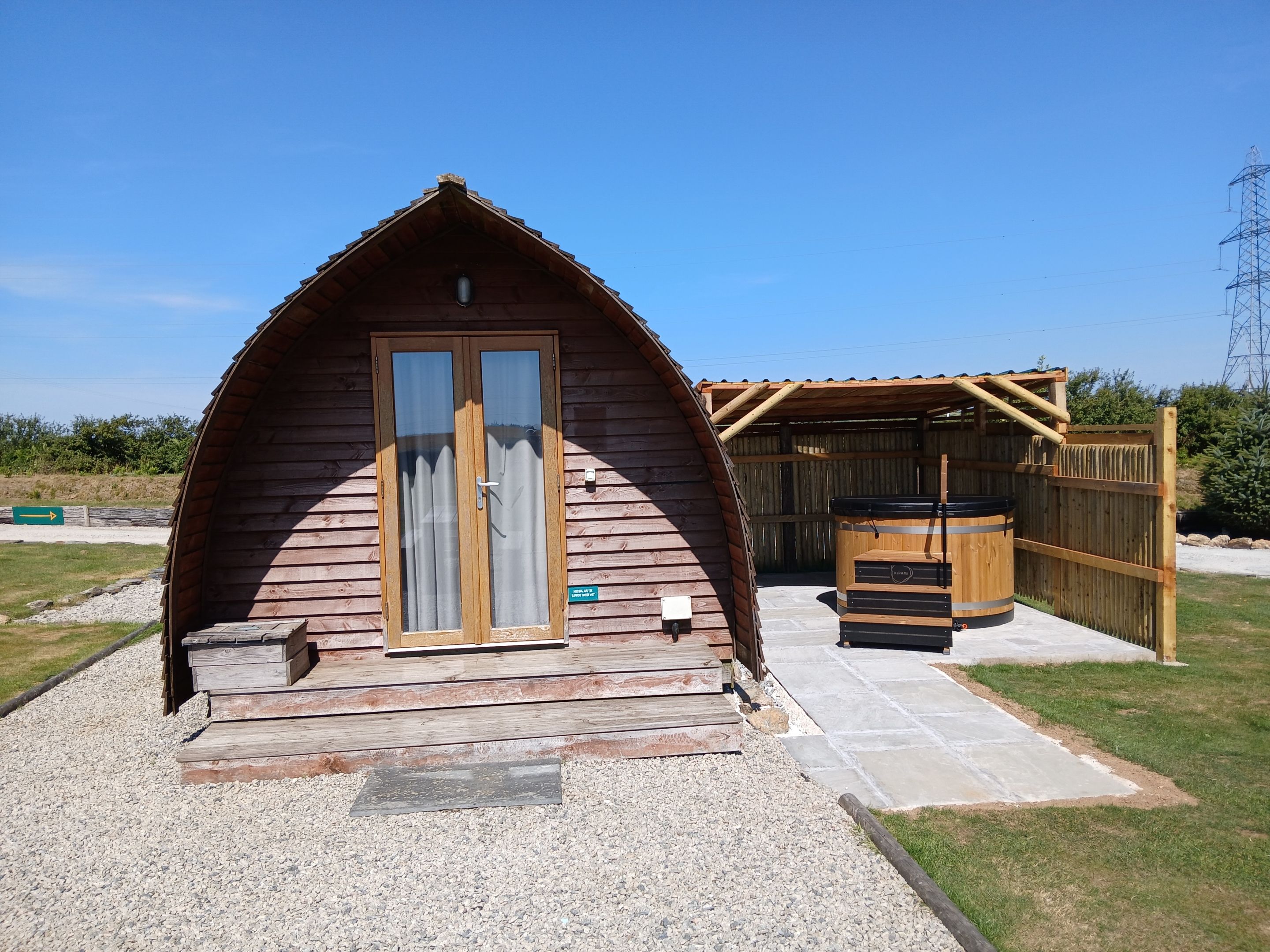 Een houten chalet met een schuine kap, een schuifdeur en een klein terras met een tafel en stoelen.