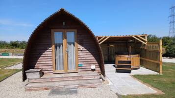 Een houten chalet met een schuine kap, een schuifdeur en een klein terras met een tafel en stoelen.