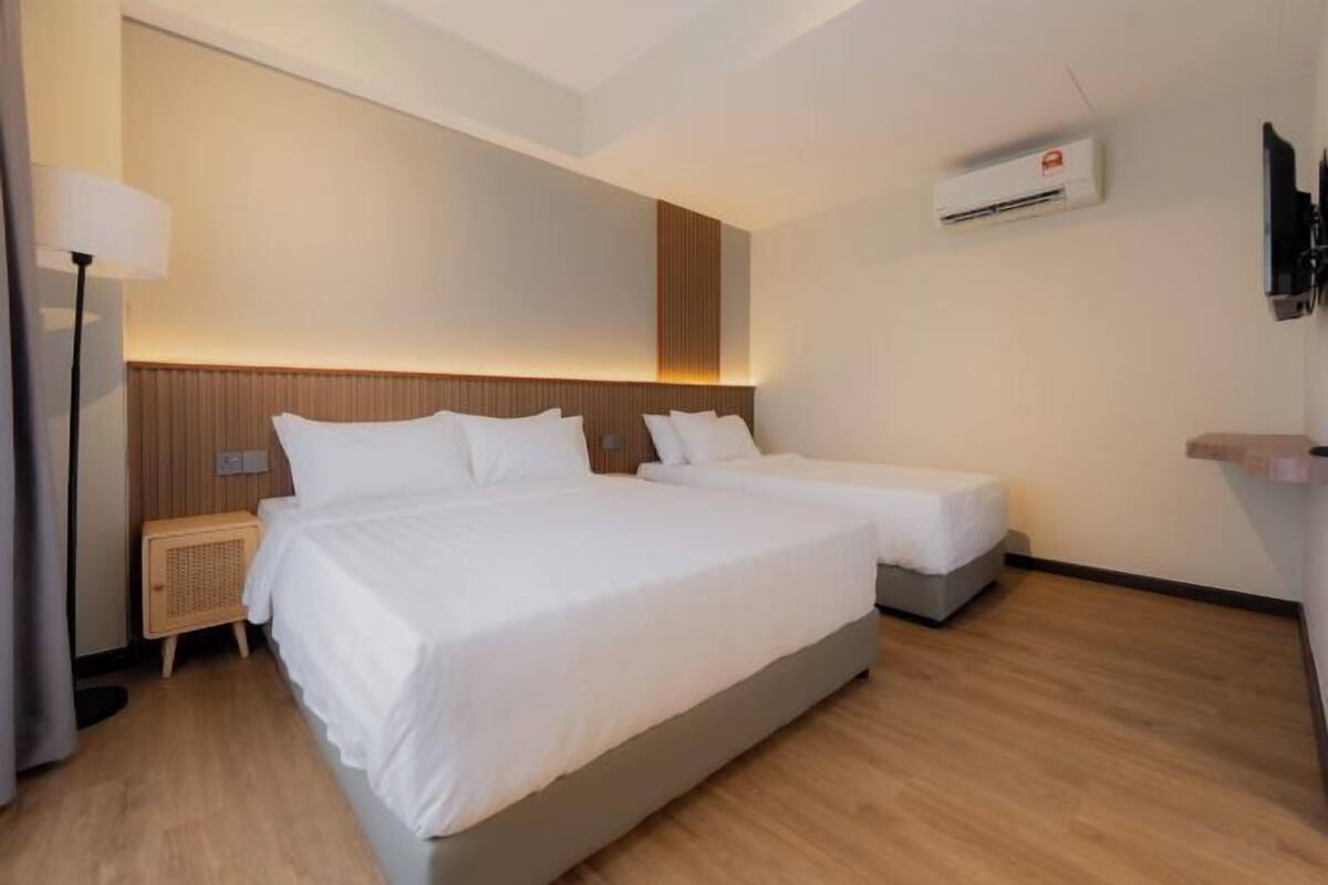 Een hotelkamer met twee bedden, een nachtkastje, een lamp, een airconditioning en een televisietoestel.