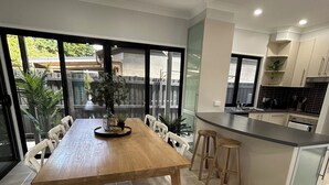 Uma cozinha moderna com mesa de jantar de madeira, cadeiras brancas e um pequeno balcão.