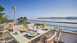 An outdoor dining area with tables and chairs, a lamp, and a view of the sea. - Bungalow in der Ferienanlage Kanegra (Buje)