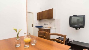 A compact kitchen with wooden cabinets, a built-in microwave, and a wall-mounted television. - Bungalow in der Ferienanlage Kanegra (Buje)