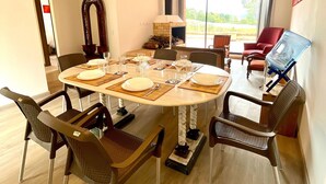 Un coin repas avec une table ronde dressée pour quatre personnes, entourée de chaises, d’une cheminée et offrant une vue sur l’extérieur.
