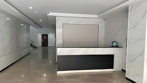 A modern reception area with a marble wall, a reception desk, and a staircase in the background.