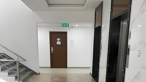 A modern hallway with a staircase, an exit door, and an elevator.