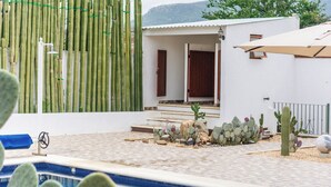 A pool area with a white building, a bamboo fence, and cacti. - Bule Villas, 1Bed/1Bath;
El Cielito Lindo: fitness room, heated pool, WiFi  (San Francisco Tutla)