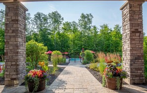 Un sendero pavimentado conduce a una zona de piscina, rodeada de abundante vegetación y plantas en macetas.