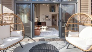 A modern home interior with a glass door entrance, wicker chairs, a sofa, and a coffee table.