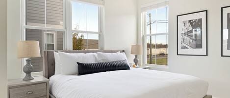 A bedroom with a large bed, two bedside tables with lamps, and a window with blinds.