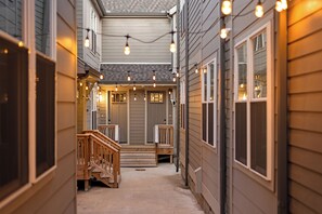 A narrow corridor with wooden steps leading to a porch, string lights overhead, and a door with a small porch area. - The Hart Suites by AvantStay (Nashville)