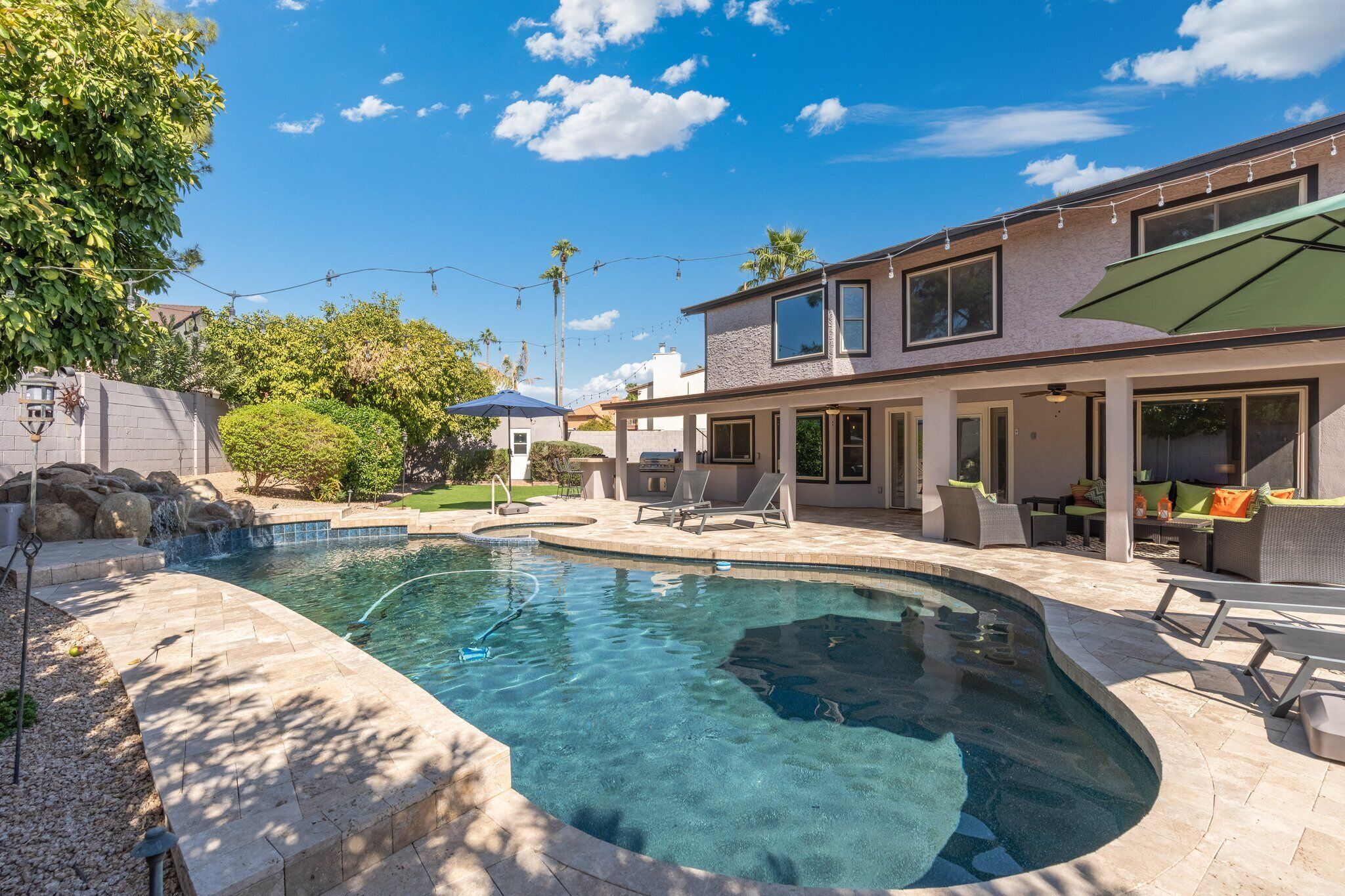 A modern house with a swimming pool, outdoor furniture, and a patio area.