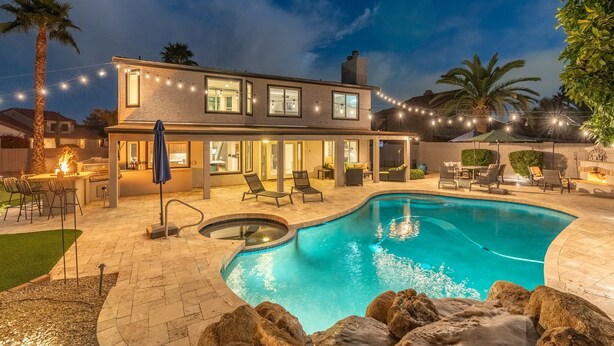 Uma casa moderna com piscina, área de estar externa e luzes de fada.
