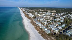Oversigtsbillede af et kystnært boligområde med ejendomme ved stranden og en lang sandstrand.