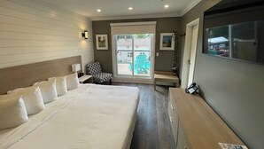 A hotel room with a large bed, a desk, a chair, and a view of the outside.