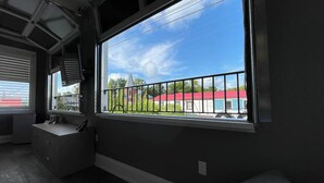 A room with a large window, a built-in bench, and a small kitchenette.