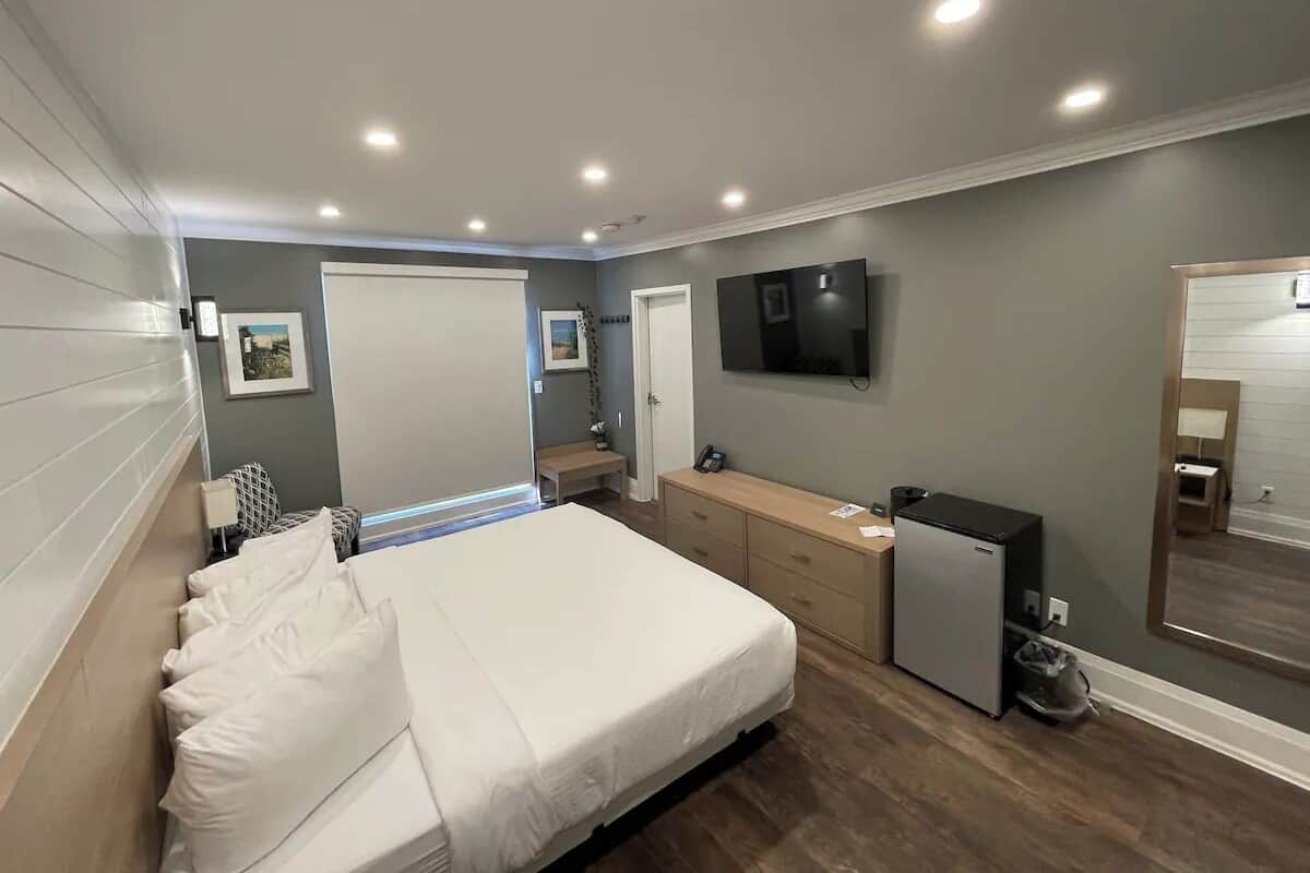 Un dormitorio con cama, cómoda, televisor y un refrigerador pequeño.