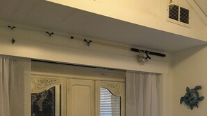 Un dormitorio con cama, cortinas, una decoración de tortuga en la pared y una ventana con persianas.