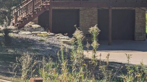 A two-story lodge with a balcony, stone foundation, and a staircase leading to the entrance. - A-frame home on Trout Stream (Stoddard)